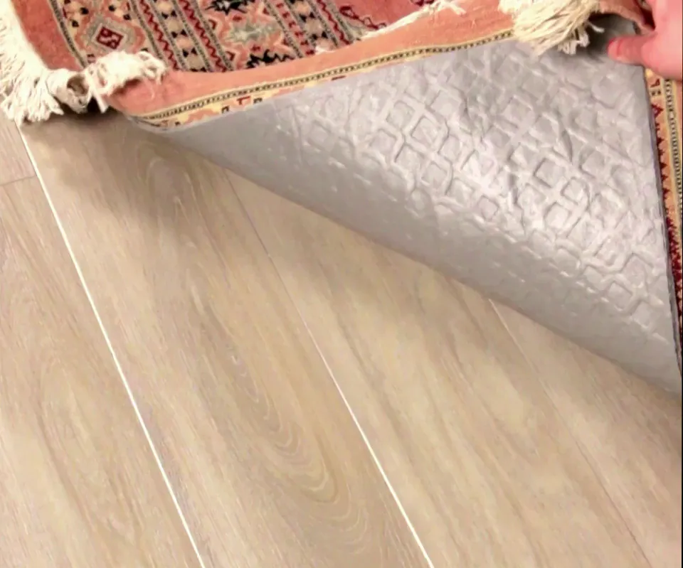 Rug corner lifted on the Rug Pad Wizard Pet Barrier pad: the same spill, and the wood floor underneath is dry